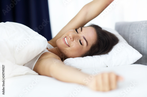 Young beautiful woman waking up in her bed fully rested