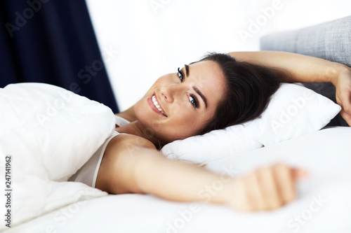 Young beautiful woman waking up in her bed fully rested