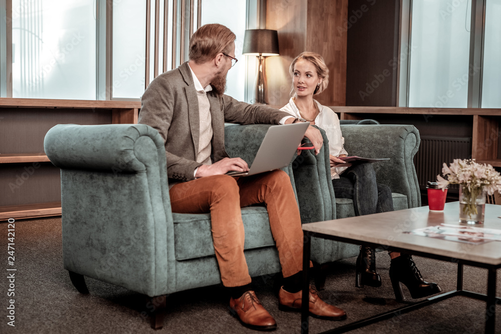 Charming girl sitting on cozy armchair near friend