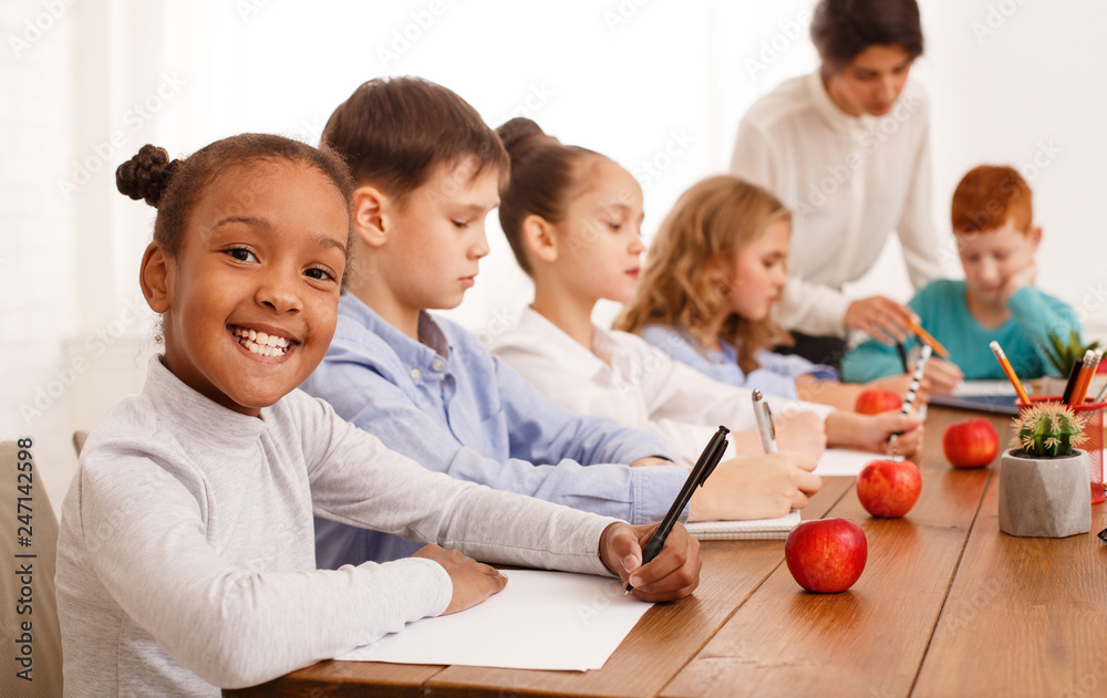 School kids writing test in classroom with teachers help School kids writing test in classroom with teachers help
