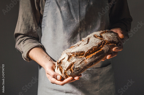 Fototapete Baker or chef holding fresh made bread