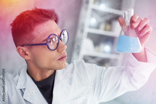 Smart student of chemistry department holding test tube with colorful liquid
