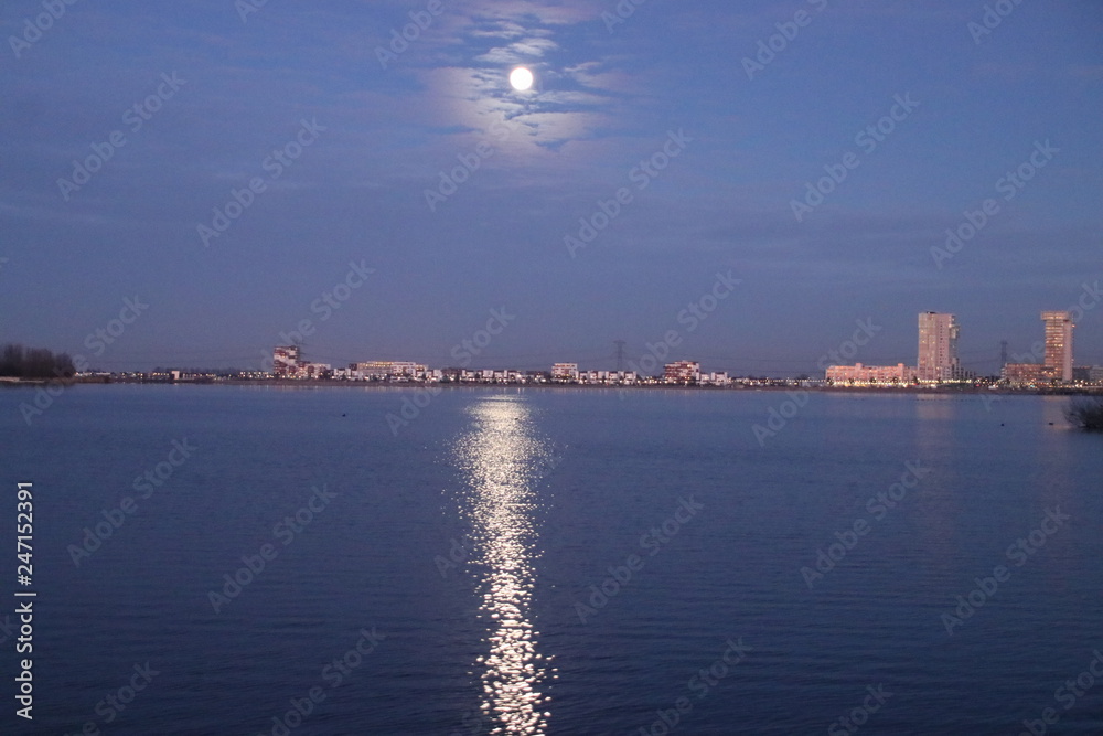 Full moon is rising above Nesselande beach reflecting on the Zevenhuizerplas as seen at Oud Verlaat just after sunset.