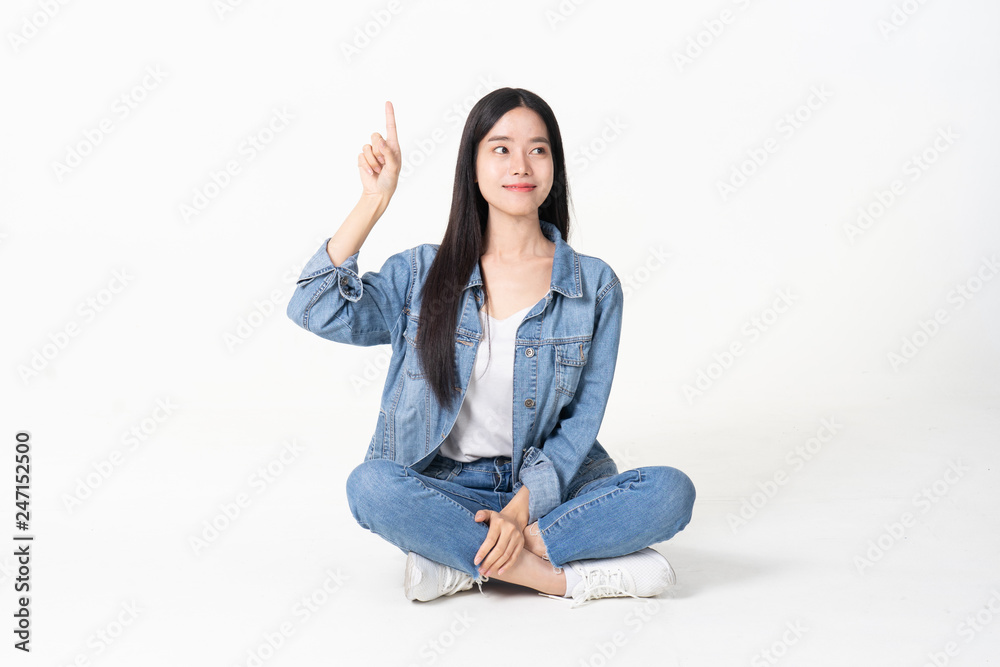 Thinking asian woman sitting on floor isolated on white background.Asian female model smiling looking up.woman pointing fingers away while sitting on a floor with legs crossed isolated Thinking asian woman sitting on floor isolated on white background.Asian female model smiling looking up.woman pointing fingers away while sitting on a floor with legs crossed isolated