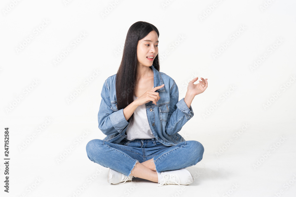 Thinking asian woman sitting on floor isolated on white background.Asian female model smiling looking up.woman pointing fingers away while sitting on a floor with legs crossed isolated Thinking asian woman sitting on floor isolated on white background.Asian female model smiling looking up.woman pointing fingers away while sitting on a floor with legs crossed isolated