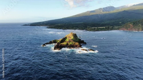 Stunning aerial early morning drone footage of ʻĀlau Island of the coast of the island of Maui near the town of Hana. Haleakala mountain volcano in the background. Alau island is a Seabird Sanctuary. photo