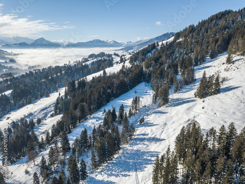 Aerial view of snow covered landscape in Switzerland, Europe. Tranquil scene with white terrain and fog in the background.