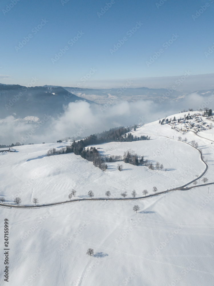 Aerial view of snow covered landscape in Switzerland, Europe. Tranquil scene with white terrain and fog in the background. Aerial view of snow covered landscape in Switzerland, Europe. Tranquil scene with white terrain and fog in the background.