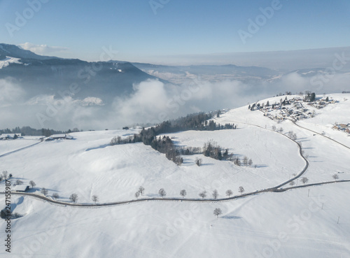 Fototapeta Naklejka Na Ścianę i Meble -  Aerial view of snow covered landscape in Switzerland, Europe. Tranquil scene with white terrain and fog in the background.