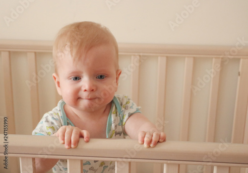 Sad first year baby is crying in his bed. Growing teeth acke
