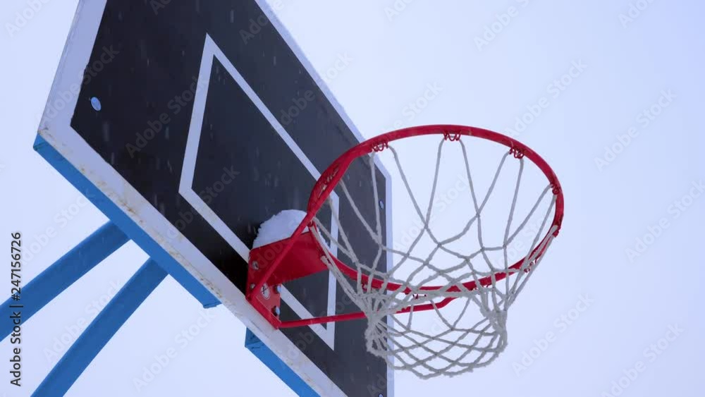 Basketball ball flies into the basket in the winter. It's snowing outside. Basketball ball flies into the basket in the winter. It's snowing outside.