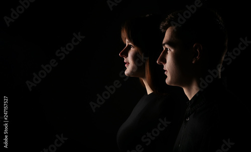 Portrait of a man and a woman in a low key. Closeup of young couple side view. Dramatic portrait