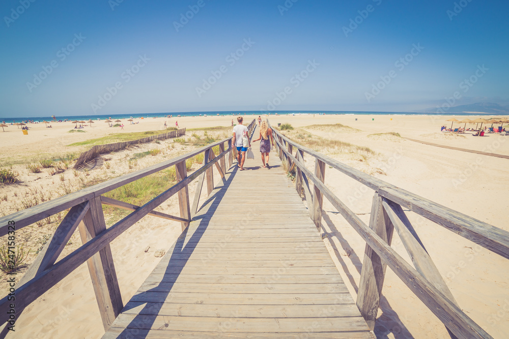 Couple walking on white bright walking path from the ocean land on the  white beach