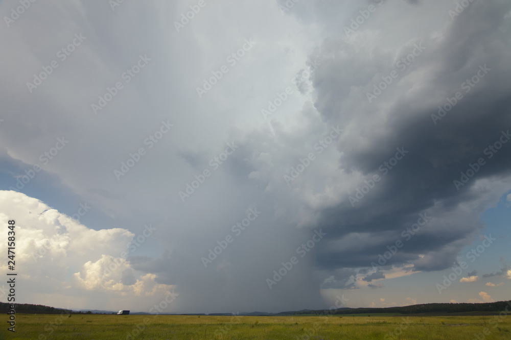 A huge storm cloud with a wall of rain in the countryside. A huge storm cloud with a wall of rain in the countryside.