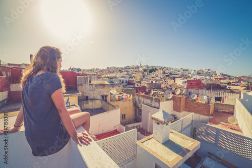 Tourist girl watching the cityscape of the medina of Tanger, Morocco. Colors of sunset