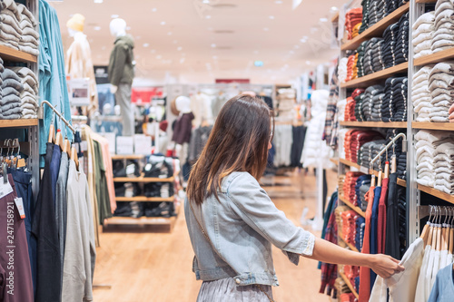 Young asian woman choosing clothes in clothing store at the mall, woman shopping lifestyle concept