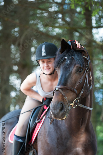 Portrait of black horse with cheerful teenage girl equestrian