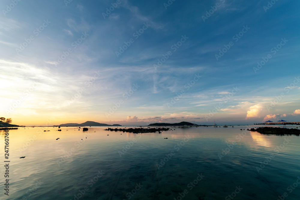 Obraz premium Dramatic sky seascape with rock in sunrise scenery and beautiful reflection in the sea