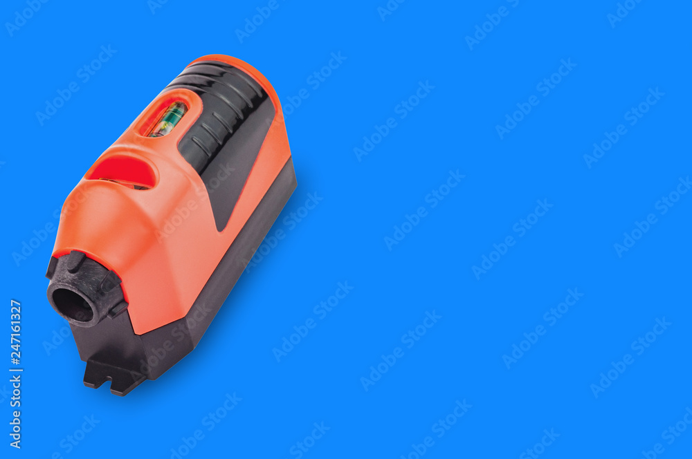 One red and black plastic laser level with water bubble for horizontal or vertical measure on blue background with copy space for your text. Building or repair concept