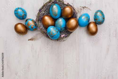 golden decorated easter eggs on white wooden background