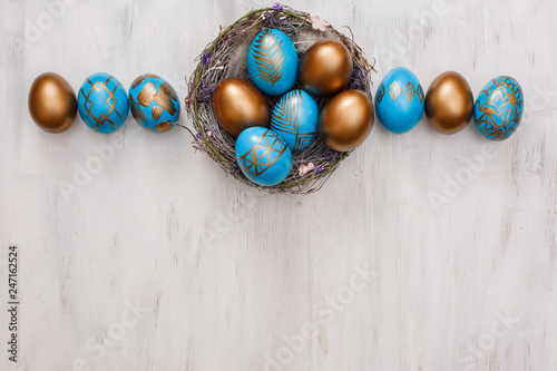 golden decorated easter eggs on white wooden background