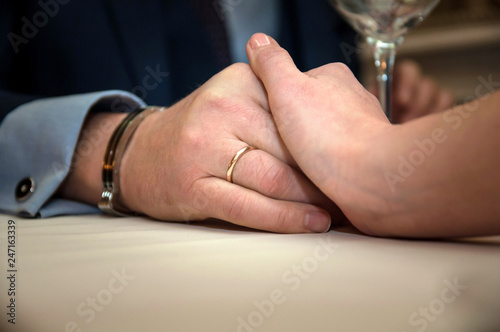 Closeup of couple hands on restaurant table with glasses of champagne. Romantic couple dinner in a luxury restaurant.