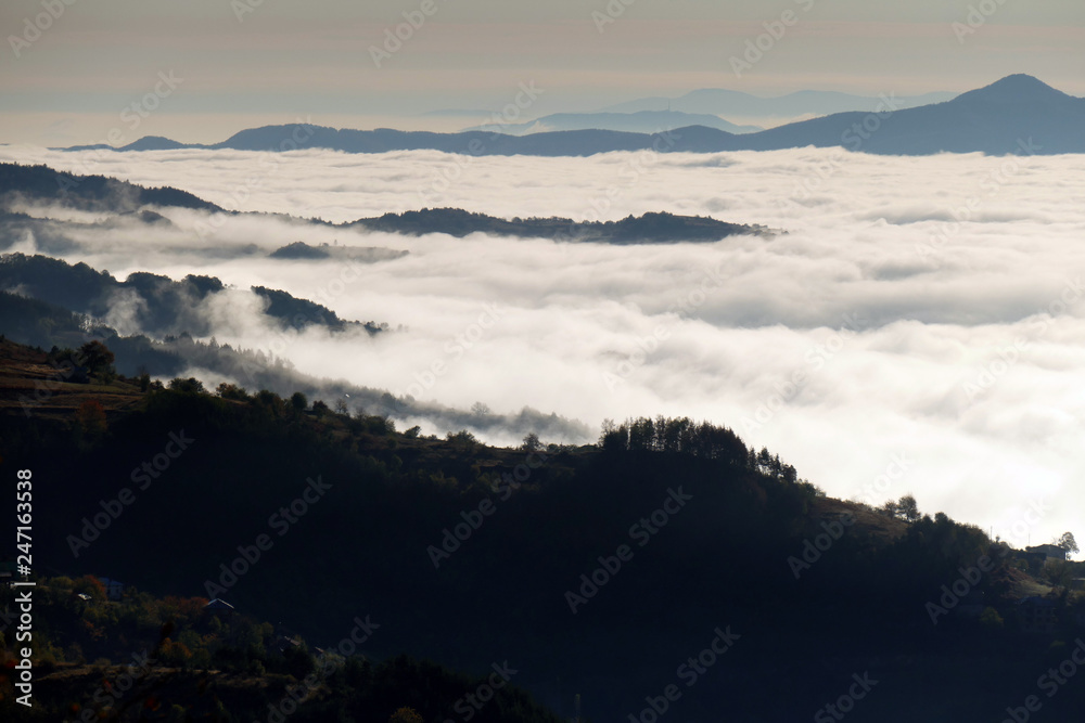 A white mist has covered Rhodope mountain in Bulgaria. Sea of thick fog. Only the high parts of the mountain can be seen.