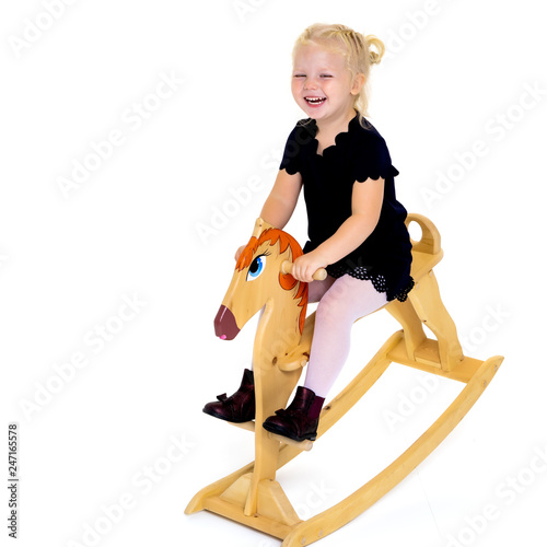 Girl swinging on a wooden horse.