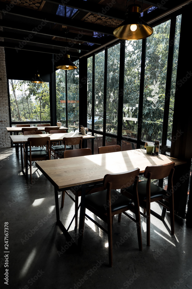 Table and chair set in modern cafe minimalistic interior design with big window and hanging ceiling lamps