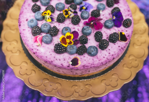 Festive cake with violet sour cream on a metal plate stand.