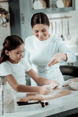 Concentrated child preparing dinner with mom in the kitchen