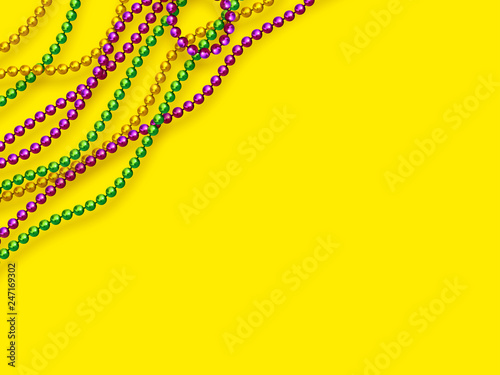 Mardi Gras beads in traditional colors. Decorative glossy realistic elements on yellow background. Copy space, top view. Vector illustration.