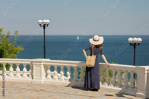 Young woman in a long dark blue skirt on the waterfront near the sea.