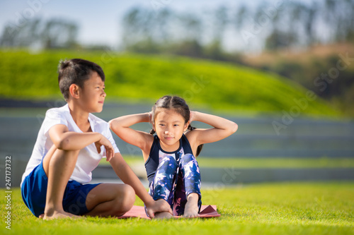 Little sporty boy and girl playing exercise or fitness outdoor, stretching muscle gymnastic