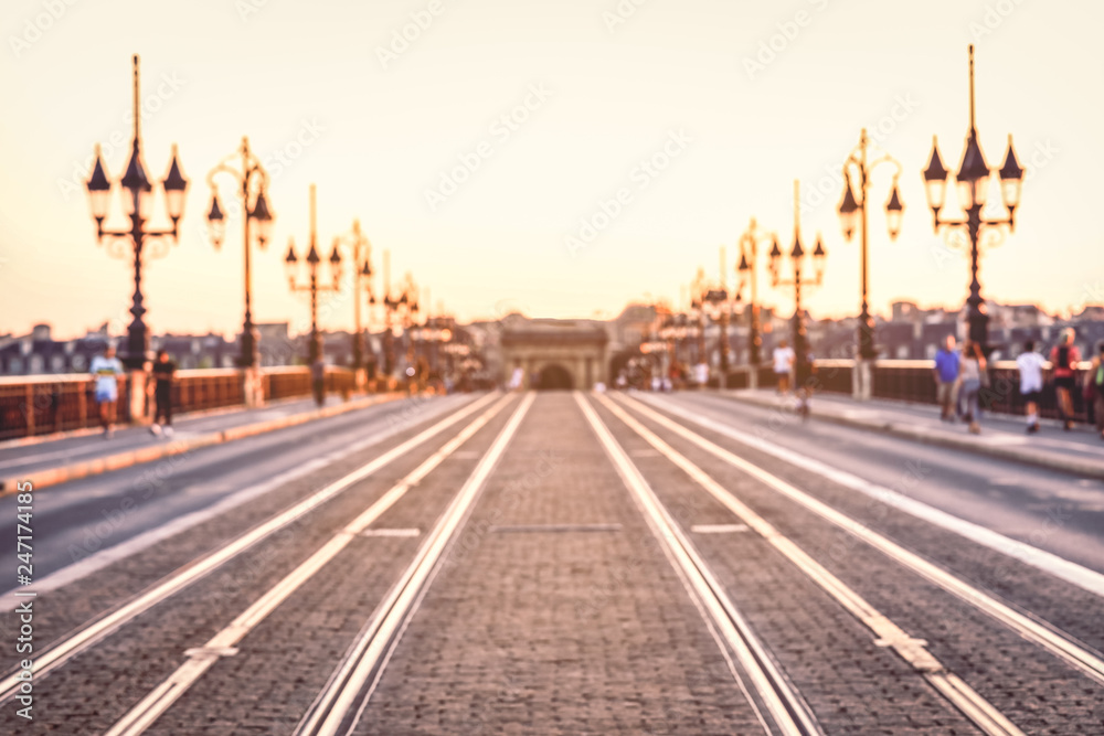 Vintage style image of blurred street with colorful lights in evening time at Pont de Pierre bridge, Bordeaux, France