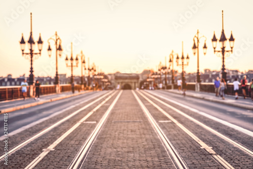 Vintage style image of blurred street with colorful lights in evening time at Pont de Pierre bridge, Bordeaux, France