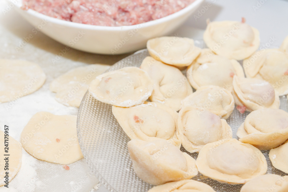 Raw and fresh dumplings lie on a glass plate