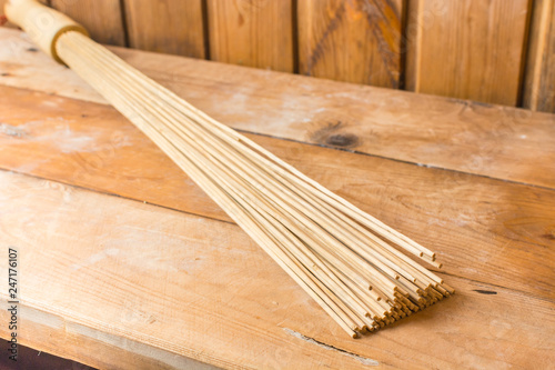 Bamboo broom lies on a wooden bench in the sauna