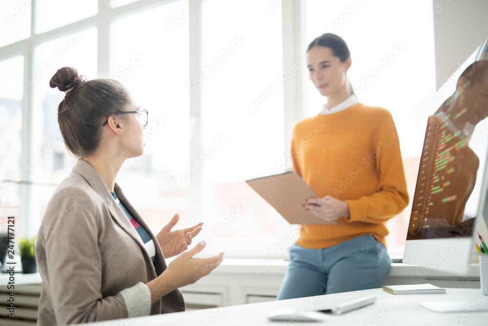 One of girls explaining her opinion or idea to colleague while brainstorming in office at start-up meeting One of girls explaining her opinion or idea to colleague while brainstorming in office at start-up meeting