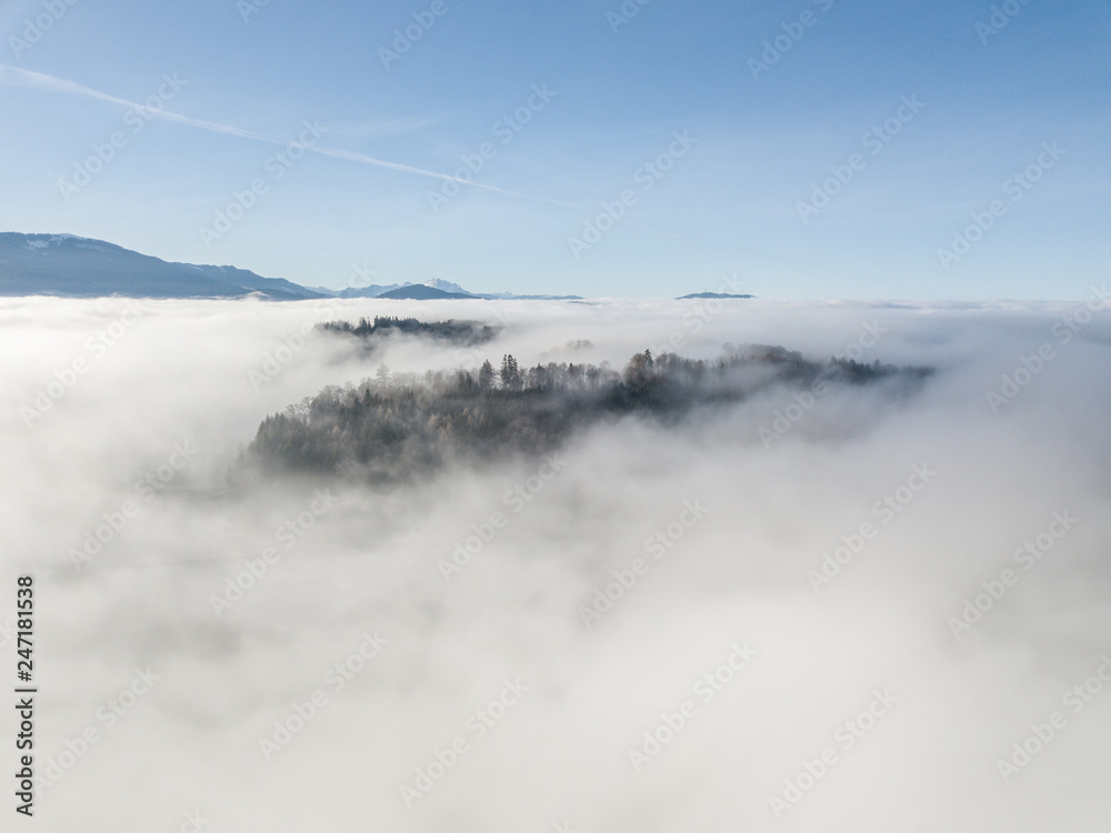 Fototapeta premium Aerial view of rural landscape in Switzerland covered with fog. Cold morning in winter with beautiful light.