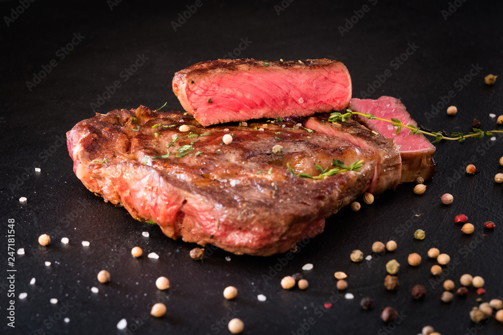 Meat cooking concept. Food composition. Rare steak and spices on black background. Meat cooking concept. Food composition. Rare steak and spices on black background.