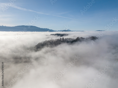 Aerial view of rural landscape in Switzerland covered with fog. Cold morning in winter with beautiful light.