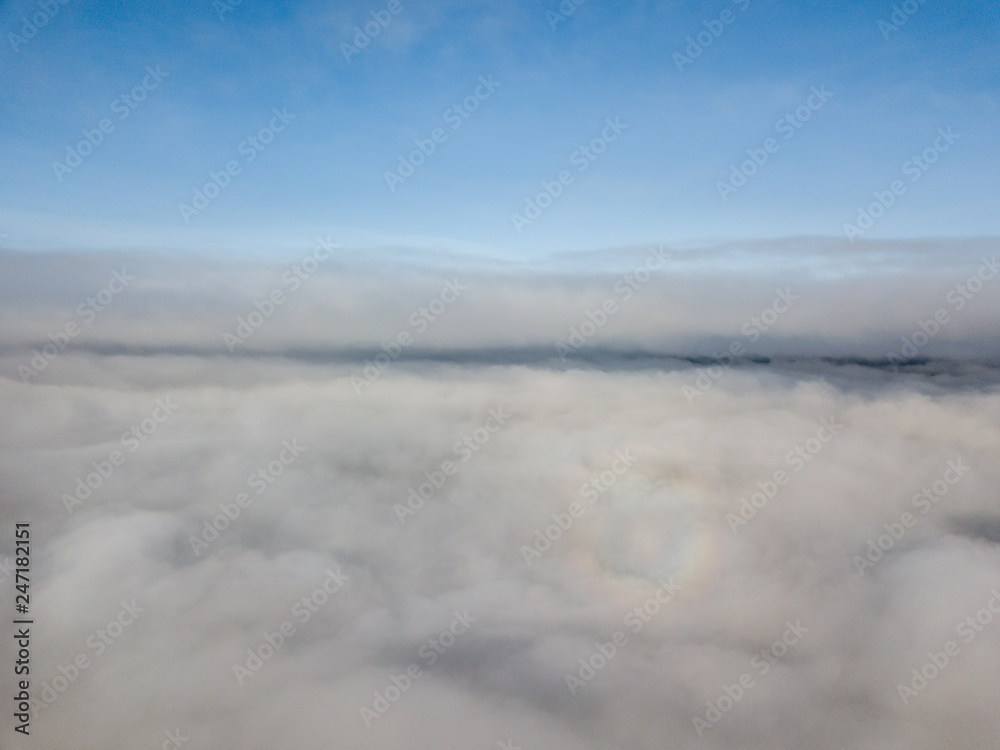 Aerial view of rural landscape in Switzerland covered with fog. Cold morning in winter with beautiful light. View from above the clouds with impressive sunlight.