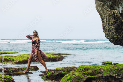 Woman portrait in a tunic and bikini on a beautiful reef beach among the rocks sensual and emotional photo