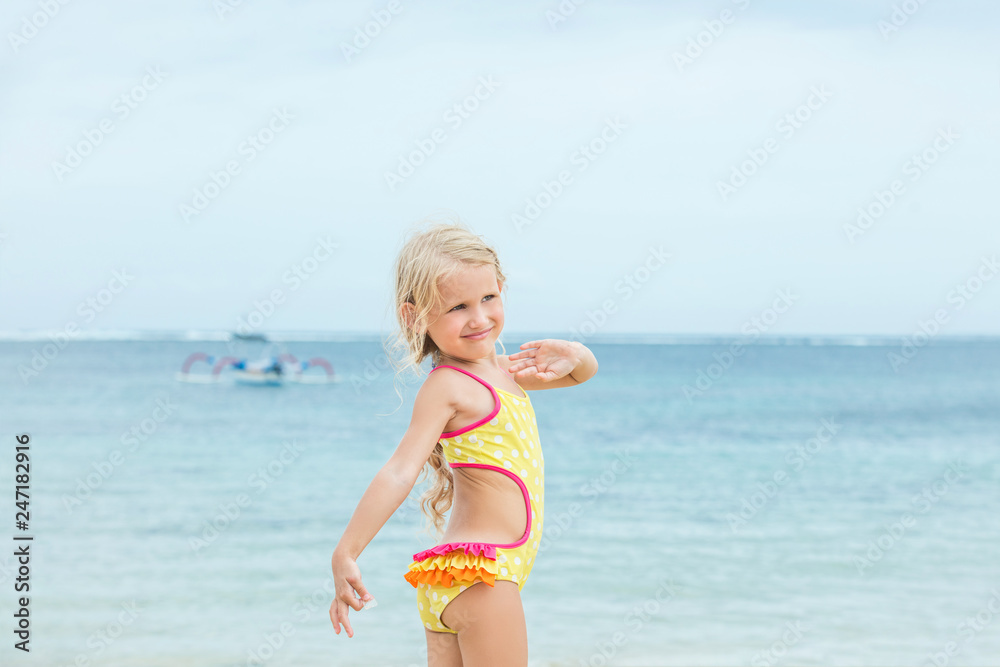 Little baby girl is beautiful and happy in a bright swimsuit in the afternoon on a Sunny beach Little baby girl is beautiful and happy in a bright swimsuit in the afternoon on a Sunny beach
