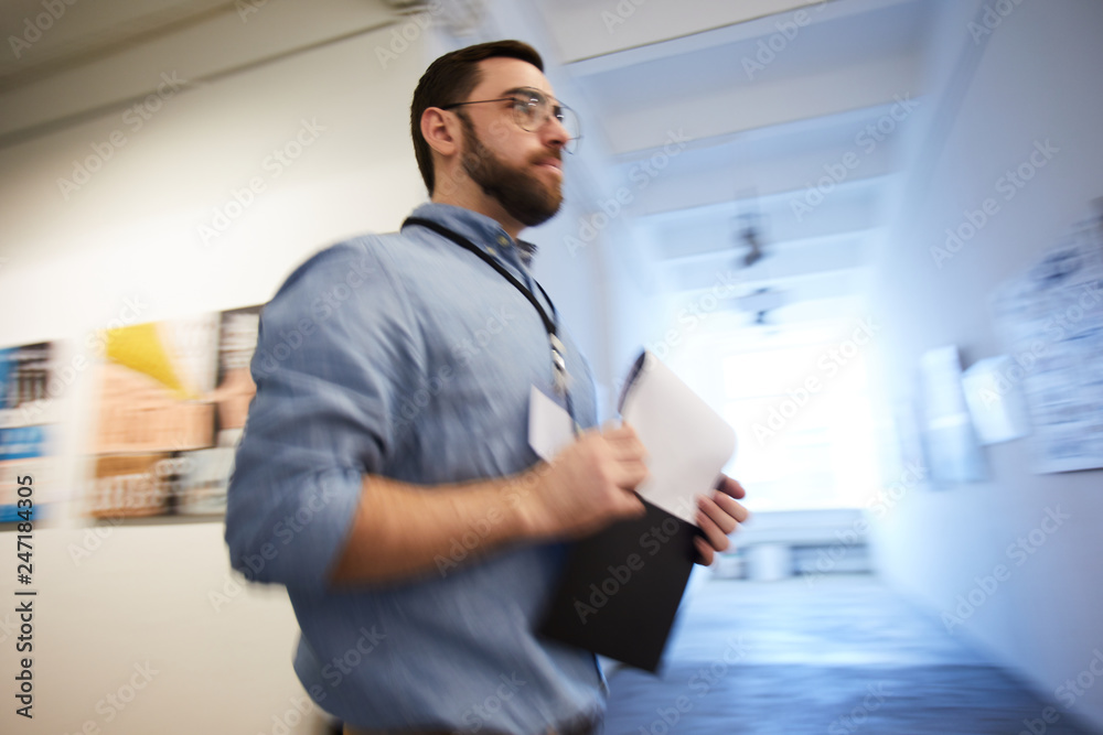 Low angle portrait of museum worker holding clipboard passing art gallery hall, copy space