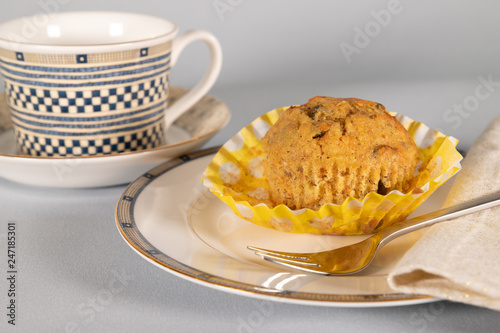 Banana chocolate chip muffin on side plate, light blue background, with shallow depth of field. photo