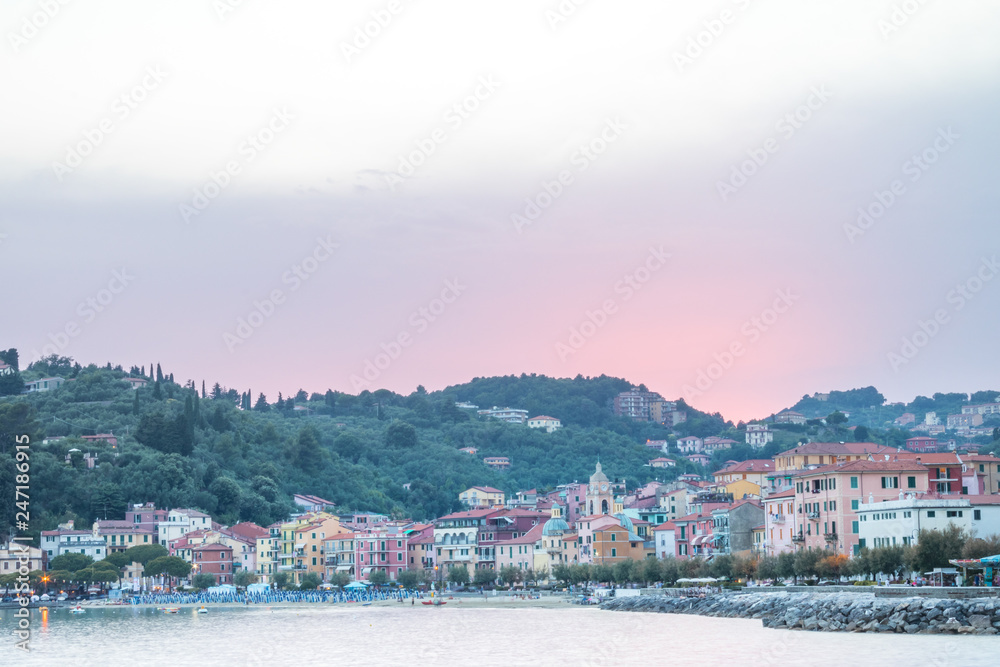 View of Lerici during sunset with a beautiful pink coloured sunset in the background over the mountains. Seen from the coast shore and shot towards the little Italian coast town.