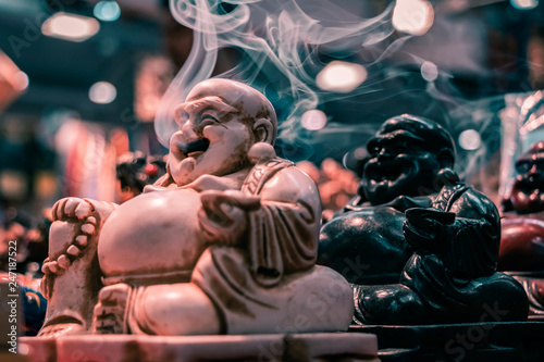 Side view of the iconic Smoking Buddha. Macro shot close up of smoke floating out of the mouth. Incense stick holder, Indian religious symbol, yoga and meditation concept.
