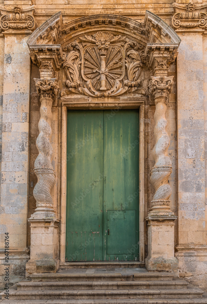 Green front door with stone carving in Ortigia island near Syracuse, Sicily, Italy 
